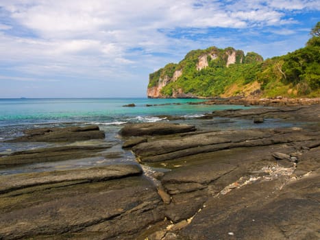 Coastline of the tropical volcanic island with big flat stones