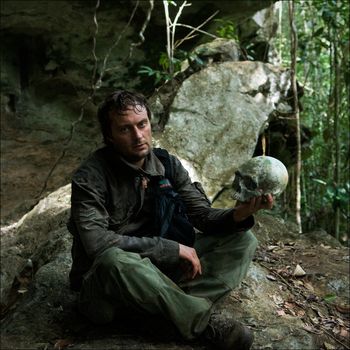 Trophy of hunters behind heads. New guinea. The traveler has control over an old trophy skull of headhunters.