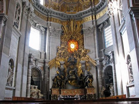 The altar in St. Peter's Basilica in Rome, Italy with sunlight shining from left to right.
