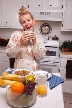 Attractive Woman In Kitchen with Fruit, Coffee, Orange Juice and Breakfast Bowls.