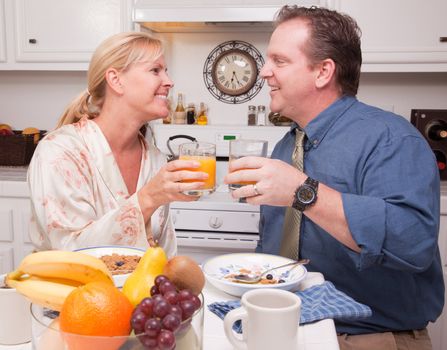 Happy Attractive Woman and Businessman In Kitchen with their Orange Juice and Breakfast.