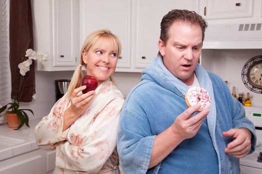 Couple in Kitchen Eating Donut and Coffee or Healthy Fruit.