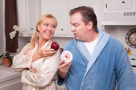 Couple in Kitchen Eating Donut and Coffee or Healthy Fruit.