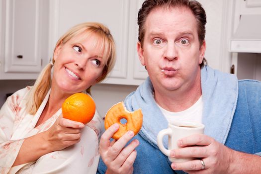 Couple in Kitchen Eating Donut and Coffee or Healthy Fruit.