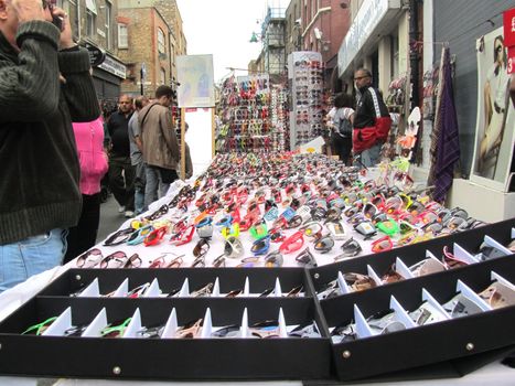 LONDON - AUGUST 15: Unidentified visitors near a sunglasses stall at Brick Lane Market on August 15, 2010 in London. Brick Lane Market is one of the largest multicultural Sunday markets in London.                 