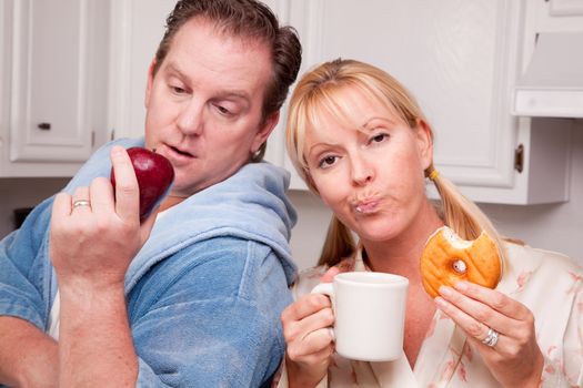 Couple in Kitchen Eating Donut and Coffee or Healthy Fruit.