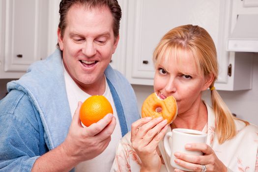 Couple in Kitchen Eating Donut and Coffee or Healthy Fruit.