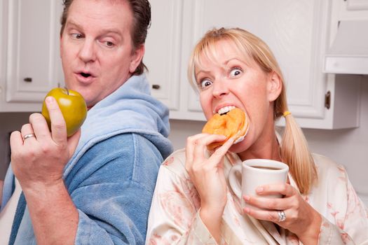 Couple in Kitchen Eating Donut and Coffee or Healthy Fruit.