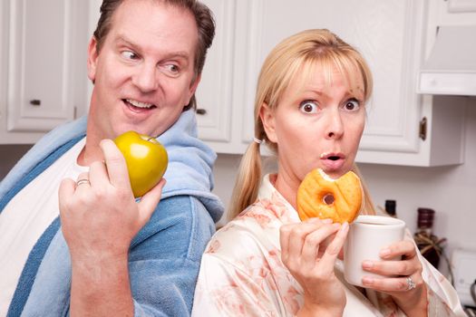 Couple in Kitchen Eating Donut and Coffee or Healthy Fruit.
