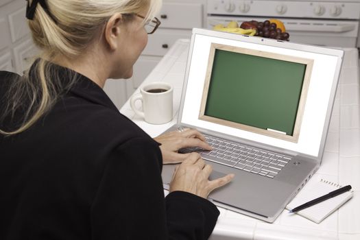 Woman In Kitchen Using Laptop with Blank Chalkboard ready for you own message. Screen can be easily used for your own message or picture. Picture on screen is my copyright as well.