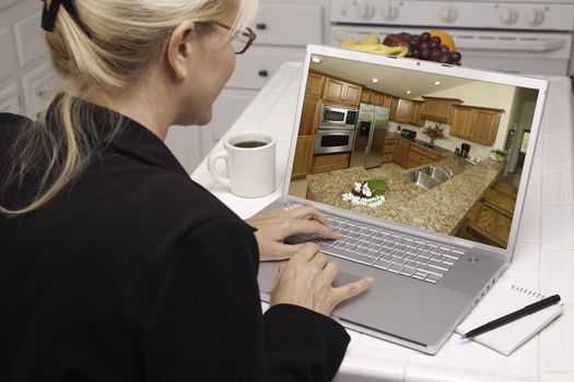 Woman In Kitchen Using Laptop to Research Home Improvement Ideas. Screen can be easily used for your own message or picture. Picture on screen is my copyright as well.