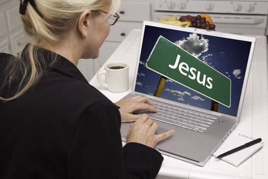 Woman In Kitchen Using Laptop with Jesus Road Sign on Screen. Screen can be easily used for your own message or picture. Picture on screen is my copyright as well.