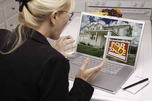 Excited Woman In Kitchen Using Laptop to Sell or Buy a Home. Screen can be easily used for your own message or picture. Picture on screen is my copyright as well.