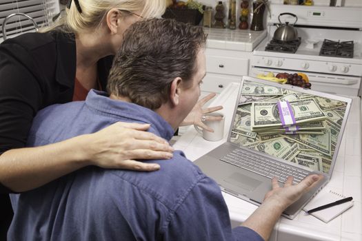 Couple In Kitchen Using Laptop to Earn or Win Money. Screen can be easily used for your own message or picture. Picture on screen is my copyright as well.