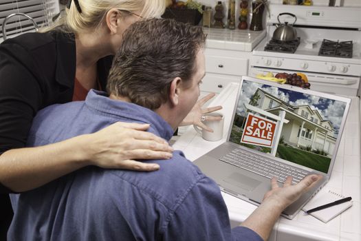 Couple In Kitchen Using Laptop to Research Real Estate. Screen can be easily used for your own message or picture. Picture on screen is my copyright as well.