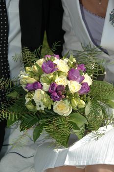 Bride and groom is holding bouquet of flowers.