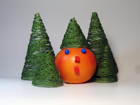 Decorated orange with face elements among souvenir spruces