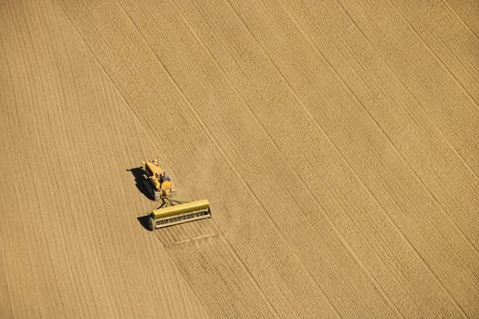 Aerial of farmer tilling crop field in farmland, USA.