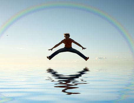 sporty man jumping under big colorful rainbow