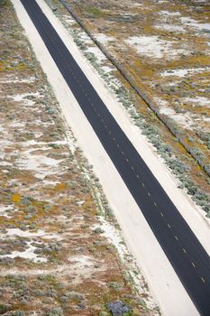 Aerial of two lane highway through desolate landscape.
