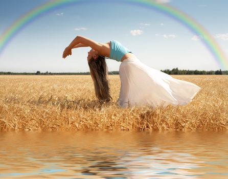 stretching woman in the meadow with rainbow and water