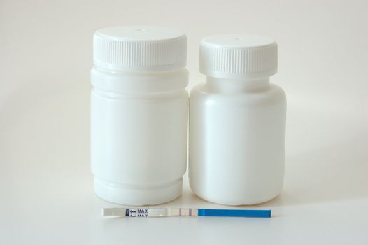 Confirmative pregnancy test and two drug's (vitamins) bottles.