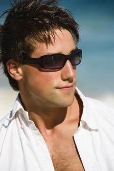 Head and shoulder portrait of attractive man wearing sunglasses on Maui, Hawaii beach.