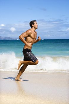 Physically fit man running on Maui, Hawaii beach.