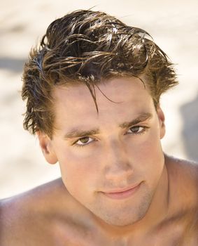 Head and shoulder portrait of handsome man on beach.