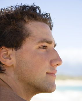 Head and shoulder profile portrait of handsome man on beach.