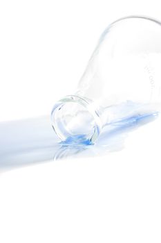 A blue liquid spilled from an erlenmeyer flask on a white background.