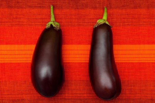 Two fresh eggplants on the red background