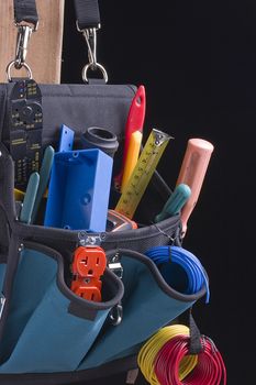 Electrician's bag with tools on a black background.