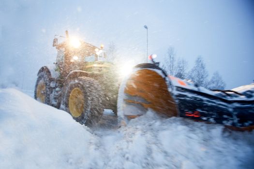 A snow plow clearing a road in winter