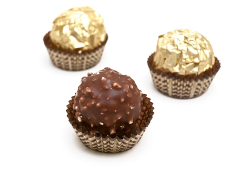 three candies in gold paper over the white background