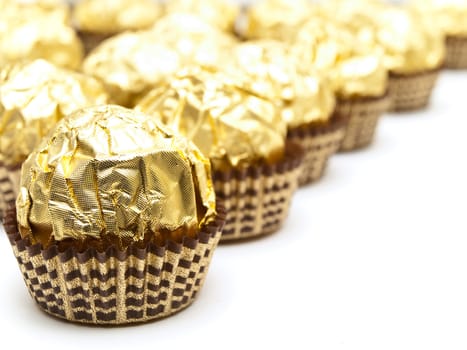 rows of candies in gold paper over the white background