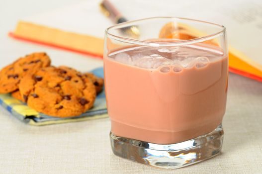 Glass of refreshing chocolate milk with cookies in the background.