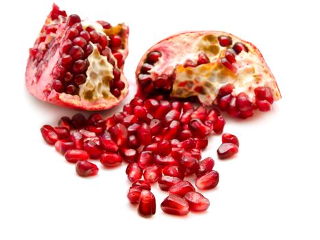 broken red pomegranate and seeds over the white