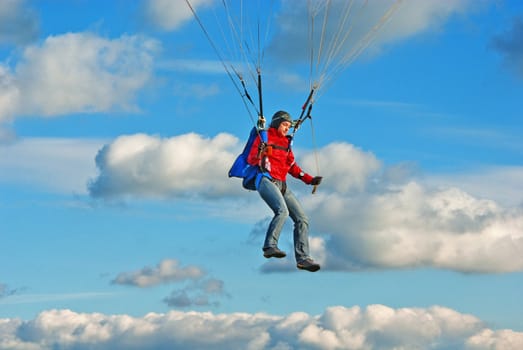 The young girl parachutist in cloudy sky  operates a parachute