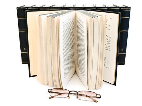 glasses against open book and books row at the white background