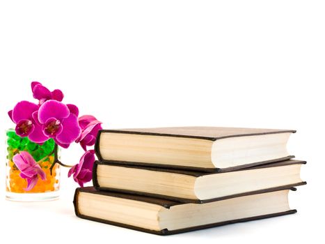 three brown books and pink orchid flower