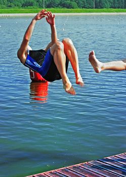 Jump in water - a back somersault. In the foreground a foot of the joker helping the jumper.