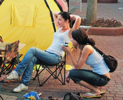 The girls-artists drinks coffee from a cup in a sity street