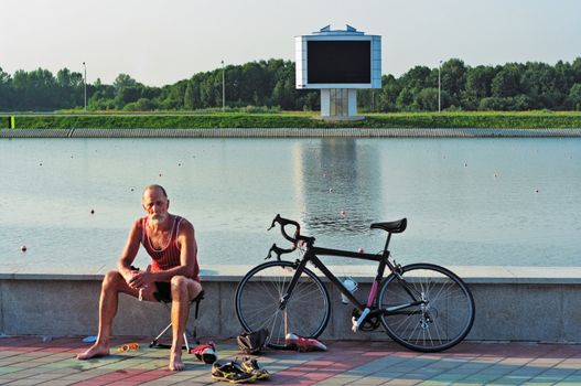 The elderly sportsman  bicyclist has a rest after end of sports competitions