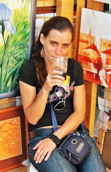 The girl-artist sits at the its pictures and drinks  in hot day