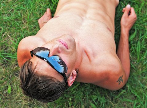 The young sportsman lays on a  stadium grass  and looks at the photographer from below upwards