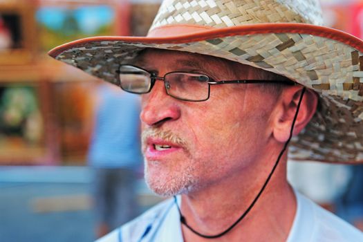 Portrait of the man in glasses and a straw hat