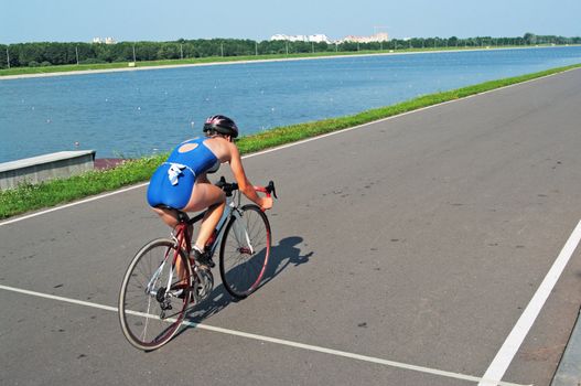 The young sportswoman goes on a bicycle on a racing line
