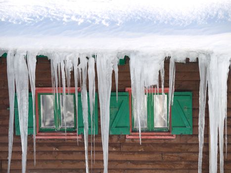 Green wooden windows with  stalactites of ice