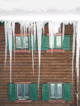 Green wooden windows with  stalactites of ice